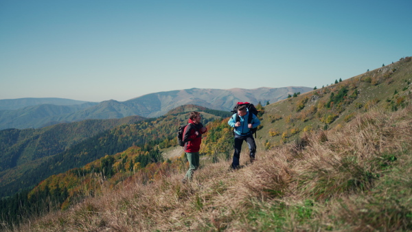 Paragliders, trekkers, mountaineers, walking up hill to a paragliding starting point, on a sunny morning in the mountains.