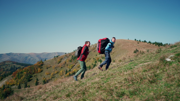 Paragliders, trekkers, mountaineers, walking up hill to a paragliding starting point, on a sunny morning in the mountains.