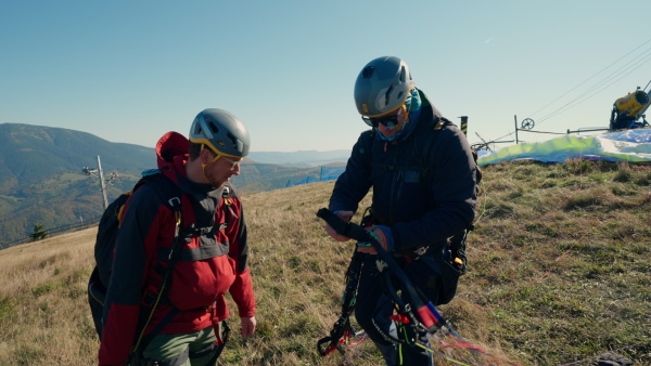 A man helping paragliding pilot to prepare for flight.