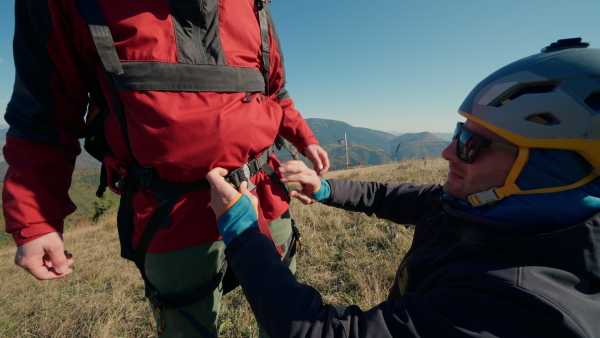 A man helping paragliding pilot to prepare for flight.