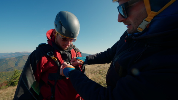 A man helping paragliding pilot to prepare for flight.