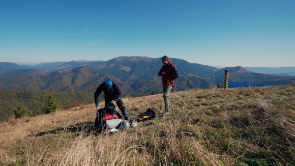 A man helping paragliding pilot to prepare for flight.