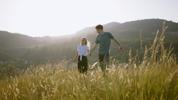 Beautiful young couple outside running through meadow and having a romantic time.