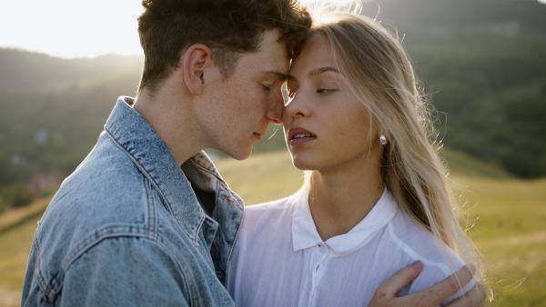 Beautiful young couple outside standing on meadow and having a romantic time.