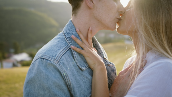 Beautiful young couple outside standing on meadow and having a romantic time.