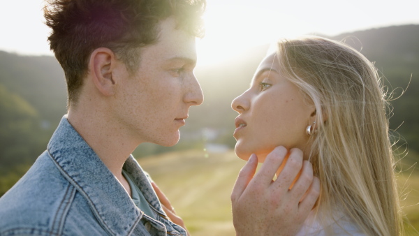 Beautiful young couple outside standing on meadow and having a romantic time.