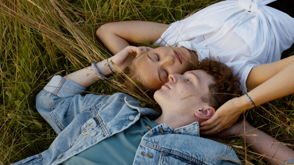 Beautiful young couple outside laying on meadow and having a romantic time.