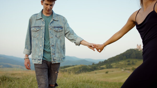 Beautiful young couple outside walking through meadow and having a romantic time.