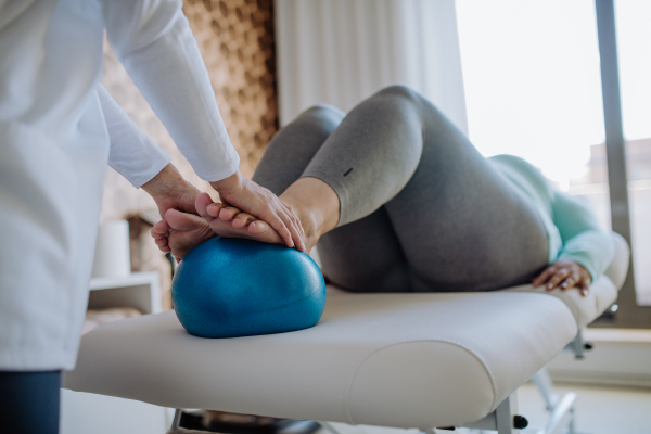 A close up hands of physiotherapist woman exercising with unrecognizable overweight woman indoors in rehabilitation center