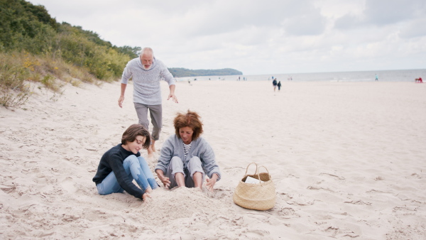 A happy grandparents with their granddaughter on beach building sand castle and having fun.A happy grandparents with their granddaughter on beach building sand castle and having fun.