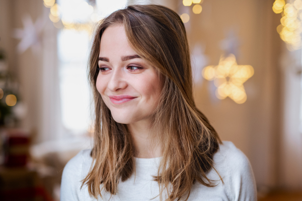 Portrait of happy young woman indoors at home at Christmas, standing.