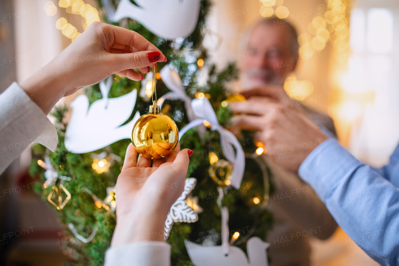 Midsection of unrecognizable family relatives indoors at home at Christmas, decorating tree.