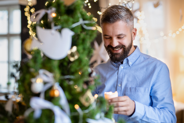 Portrait of mature man indoors at home at Christmas, holding candle.