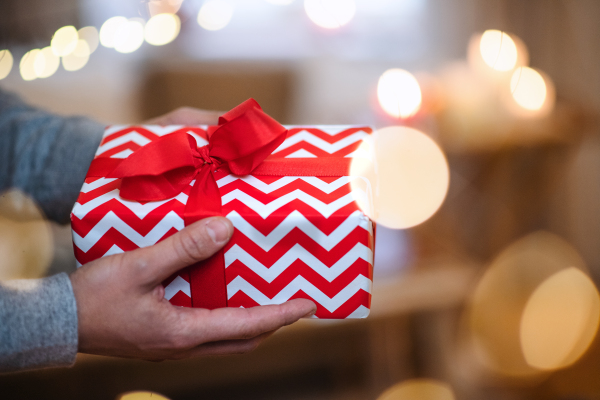 Close-up of hands of unrecognizable mature man indoors at home at Christmas, holding present.