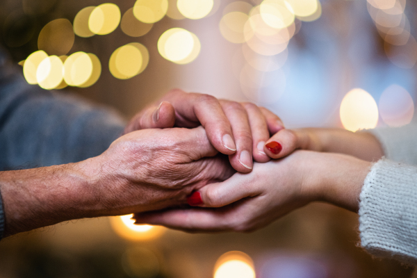 Hand of unrecognizable senior man holding hand of young woman indoors at Christmas, close-up.