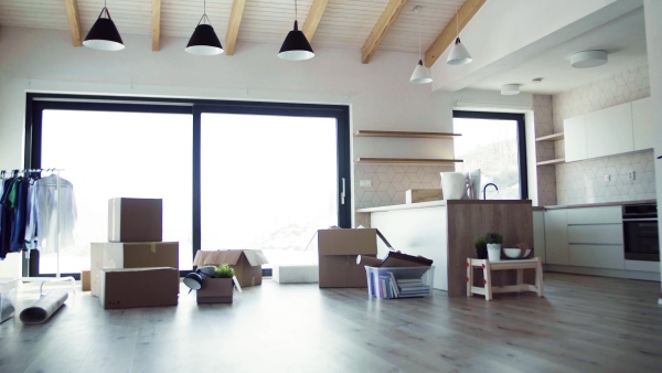 Moving boxes, clothes rack and small furniture on the floor in new home. A moving in new home concept.