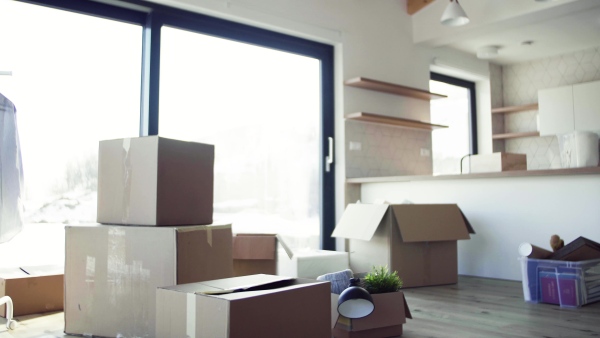 Moving boxes, clothes rack and small furniture on the floor in new home. A moving in new home concept.