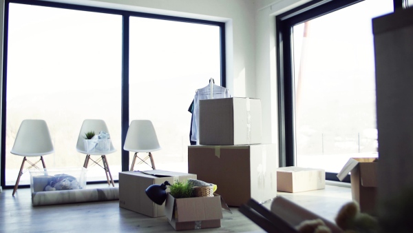 Moving boxes, clothes rack and small furniture on the floor in new home. A moving in new home concept.