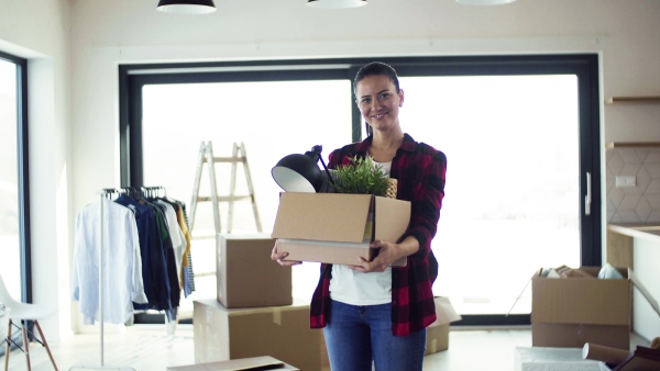 A young happy woman furnishing new house, unpacking stuff. A moving in new home concept.