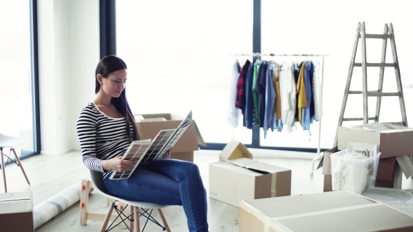 A young woman moving in new home, looking at color swatch. A moving in new home concept.