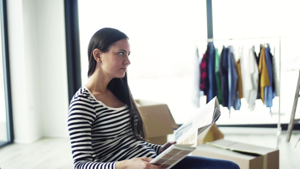 A young woman moving in new home, looking at color swatch. A moving in new home concept.