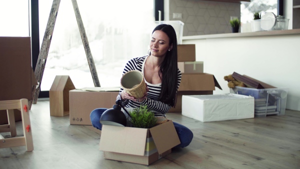 A young happy woman furnishing new house, unpacking stuff. A moving in new home concept.