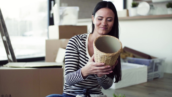 A young happy woman furnishing new house, unpacking stuff. A moving in new home concept.