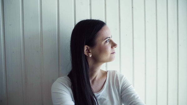 A cheerful young woman sitting on the floor in new home, resting. A moving in new home concept. Slow motion.