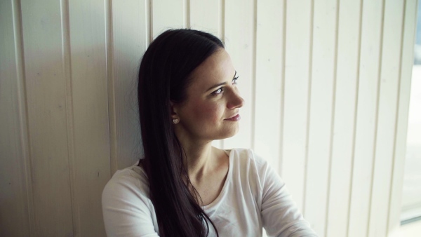 A cheerful young woman sitting on the floor in new home, resting. A moving in new home concept. Slow motion.