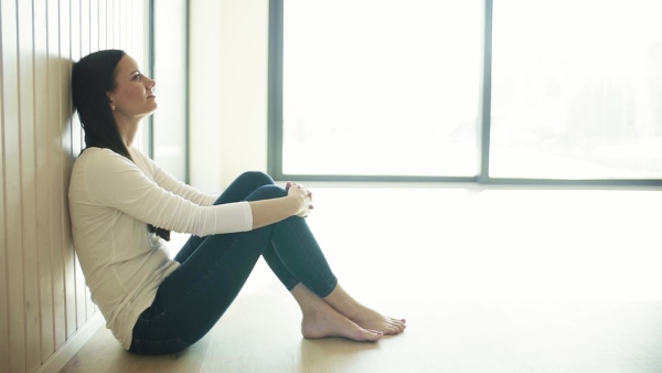 A happy young woman sitting on the floor in new home, resting. A moving in new home concept. Slow motion.