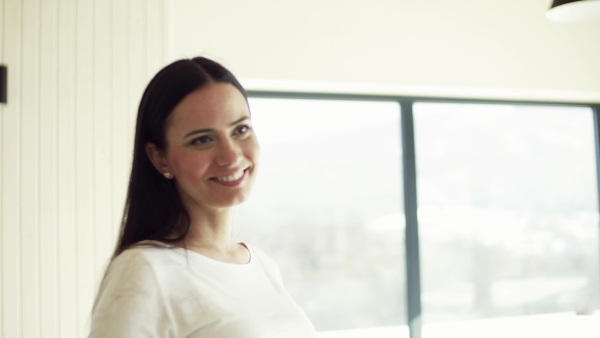 A portrait of happy young woman standing in new home.