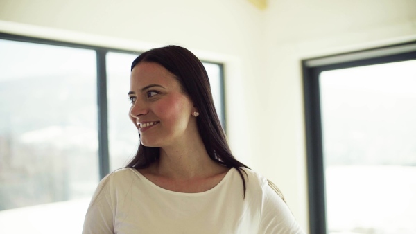 A portrait of happy young woman standing in new home. Slow motion.