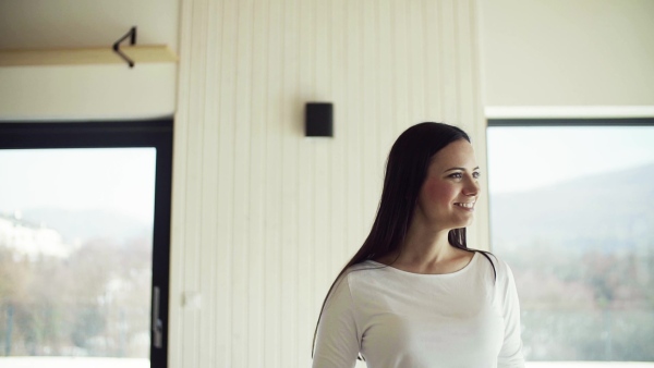 A portrait of happy young woman standing in new home. Slow motion.