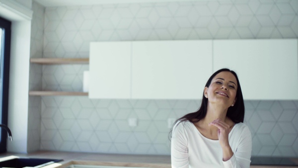 A cheerful young woman leaning on kitchen counter in new home, resting. A moving in new home concept.