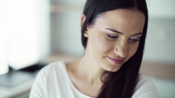 A close-up portrait of young woman indoors in new home. Slow motion.