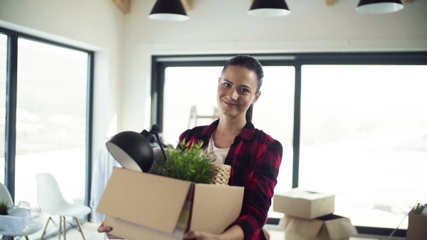 A cheerful young woman furnishing new house, holding a box. A moving in new home concept. Slow motion.