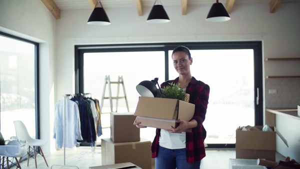 A young happy woman furnishing new house, holding a box. A moving in new home concept. Slow motion.