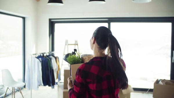 A cheerful young woman furnishing new house, carrying a box. A moving in new home concept. Slow motion.