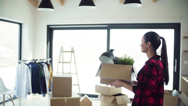 A young happy woman furnishing new house, carrying a box. A moving in new home concept. Slow motion.