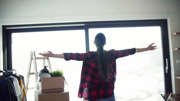 A young excited woman furnishing new house, spinning when unpacking stuff. A moving in new home concept. Slow motion.