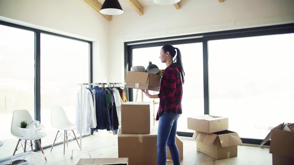 A young happy woman furnishing new house, carrying a box. A moving in new home concept. Slow motion.