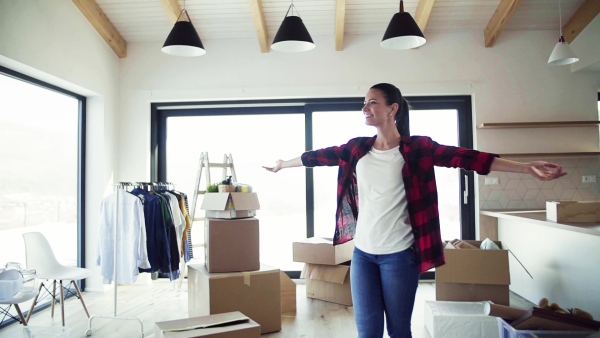 A young excited woman furnishing new house, spinning when unpacking stuff. A moving in new home concept. Slow motion.