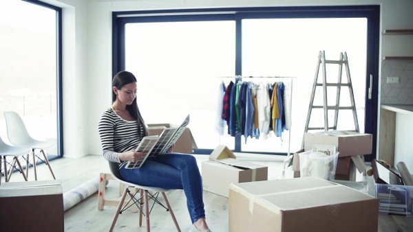 A young woman moving in new home, looking at color swatch. A moving in new home concept. Slow motion.