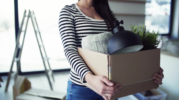 A young happy woman furnishing new house, holding a box. A moving in new home concept. Slow motion.