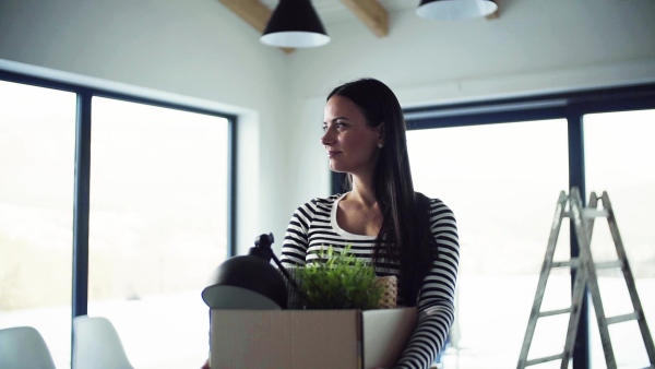 A young happy woman furnishing new house, holding a box. A moving in new home concept. Slow motion.