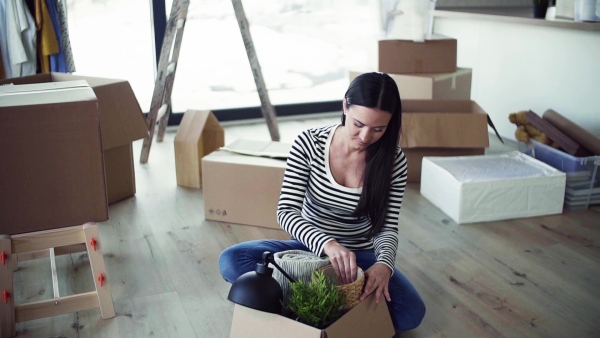 A young happy woman furnishing new house, unpacking stuff. A moving in new home concept. Slow motion.