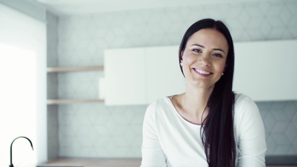 A cheerful young woman sitting on kitchen counter in new home, resting. A moving in new home concept.