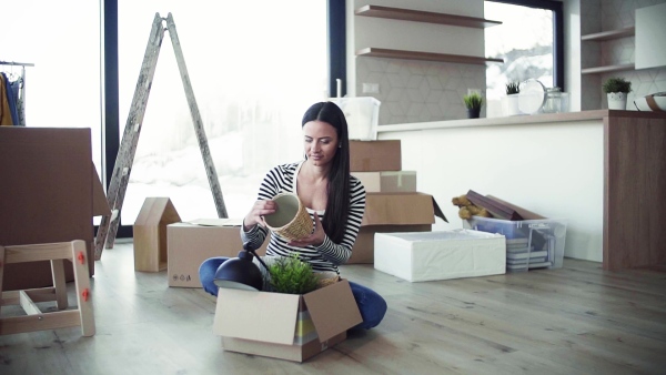 A young happy woman furnishing new house, unpacking stuff. A moving in new home concept. Slow motion.