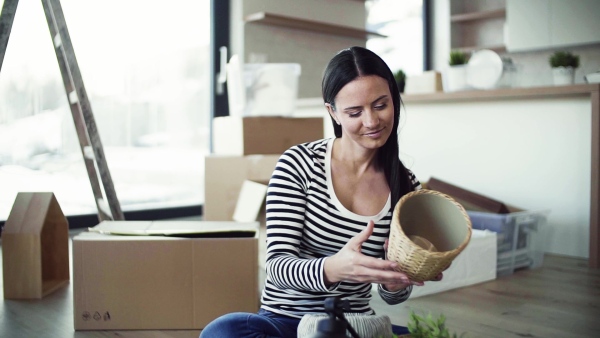 A young happy woman furnishing new house, unpacking stuff. A moving in new home concept. Slow motion.