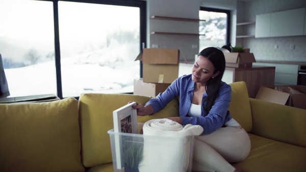 A young woman moving in new home, sitting on sofa and resting. A moving in new home concept. Slow motion.